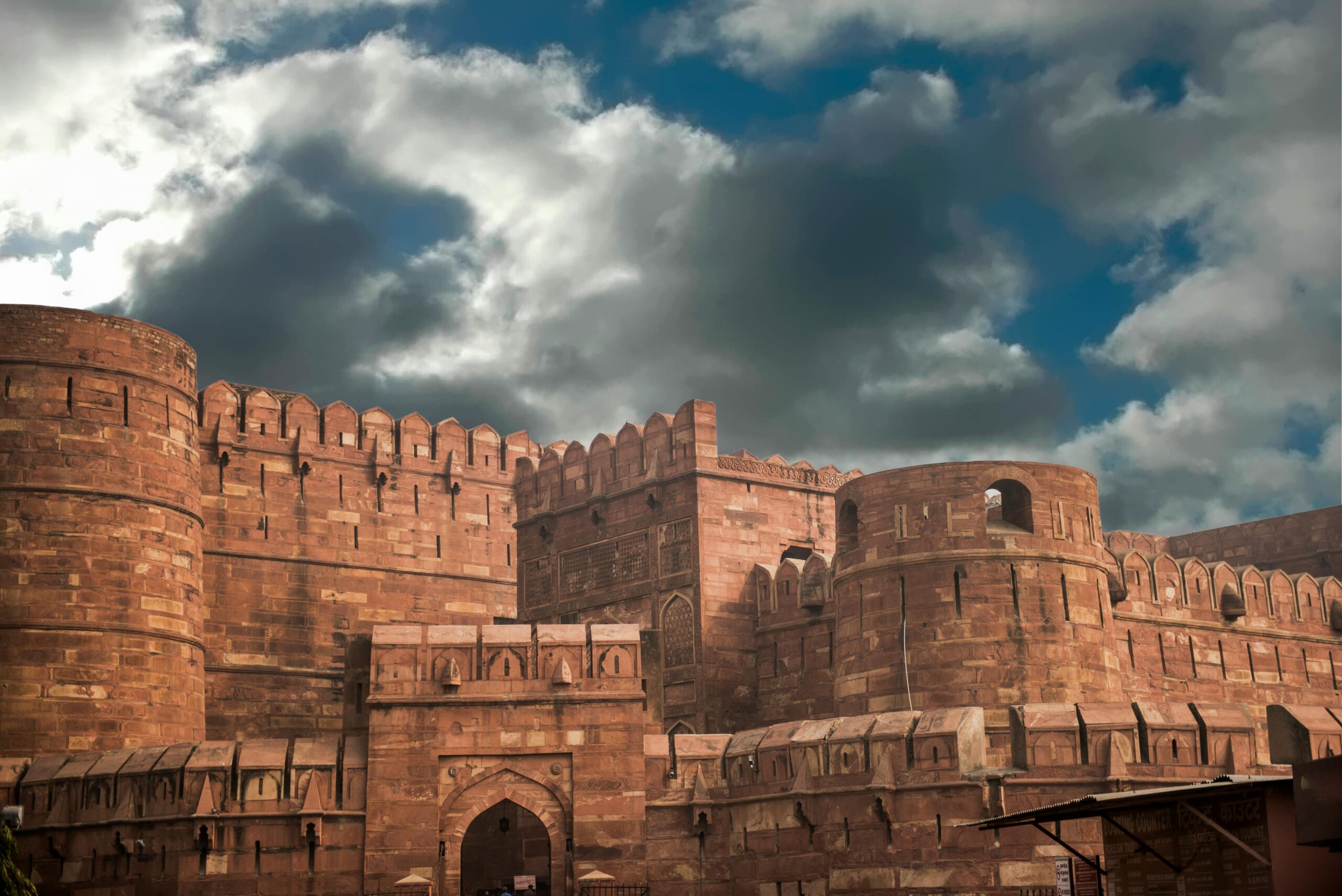 Historic red sandstone fort with intricate architecture under a cloudy sky.